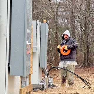 Journeyman Electrician, Brandon, stands in front of a company work vehicle